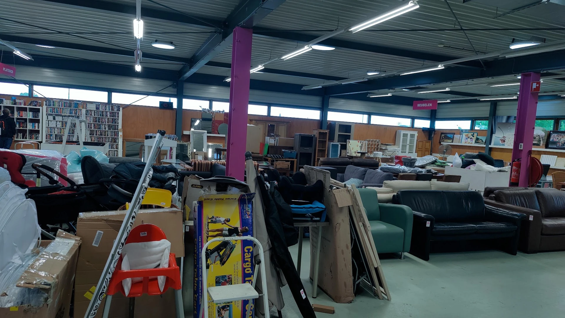 Ruim winkelinterieur met meubels, stellingen en diversen spullen uitgestald
