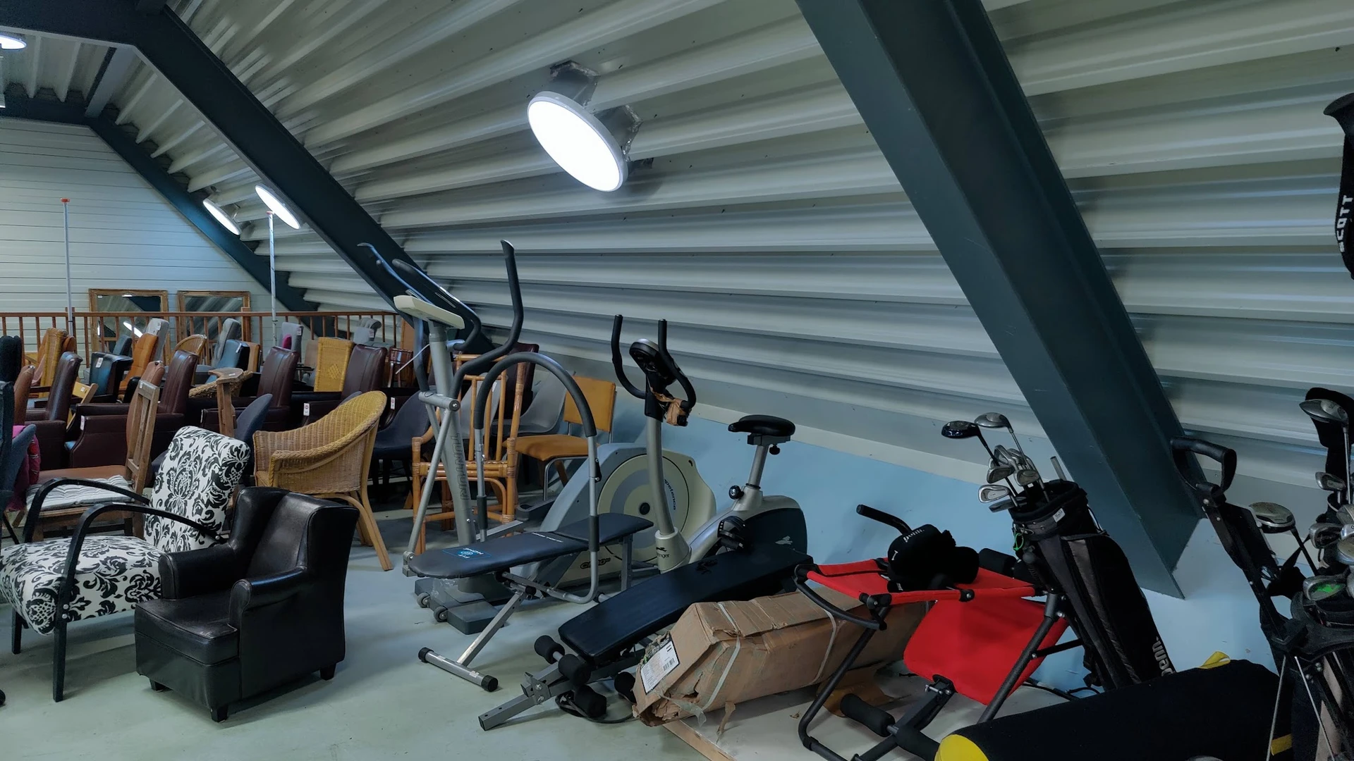 Magazijnruimte met sportapparatuur, stoelen en diverse spullen onder Led-verlichting