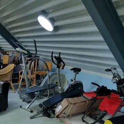 Magazijnruimte met sportapparatuur, stoelen en diverse spullen onder Led-verlichting