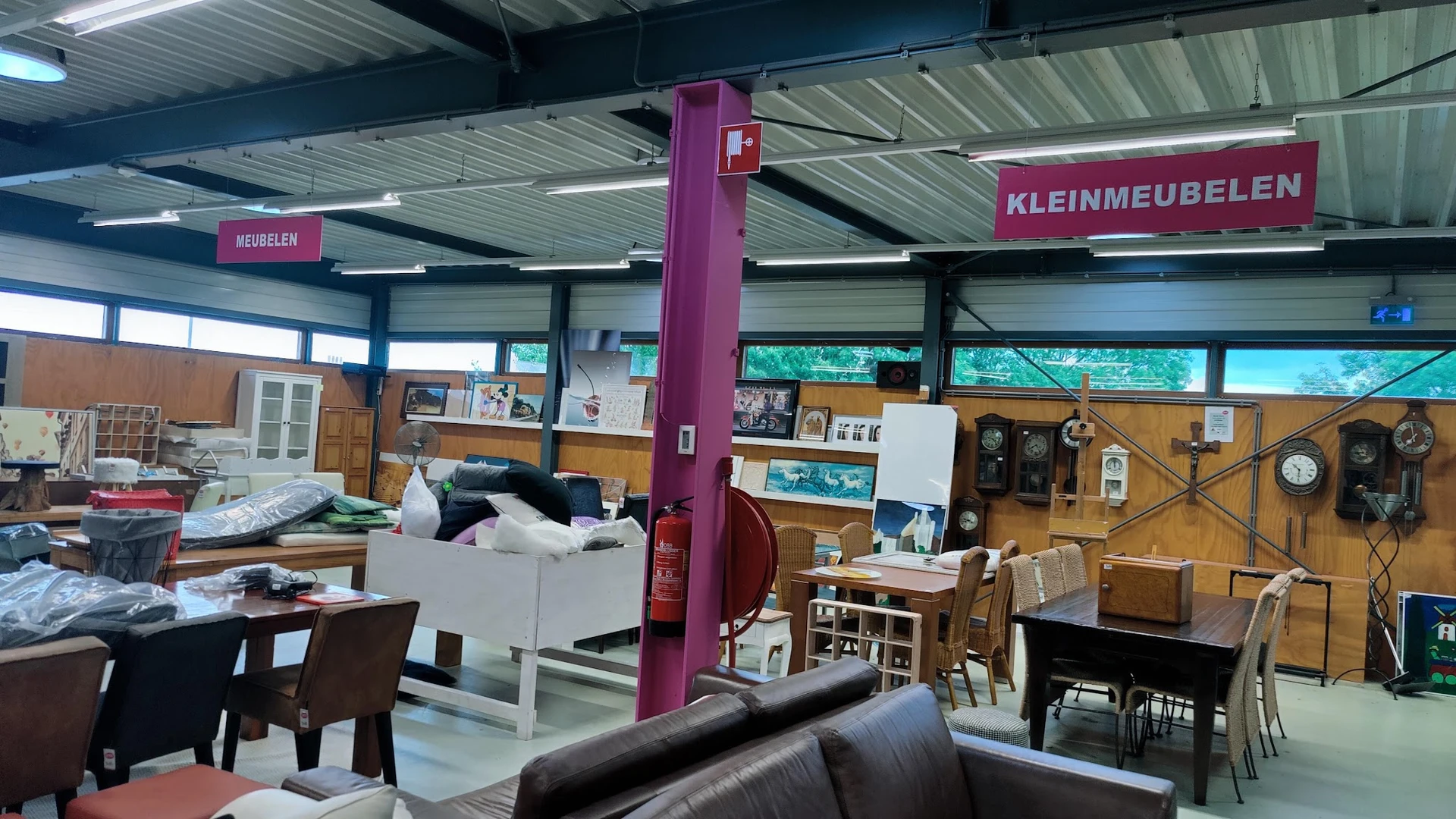 Winkelvloer met meubels, stellingen, en verschillende afdelingen in een ruime kringloopwinkel
