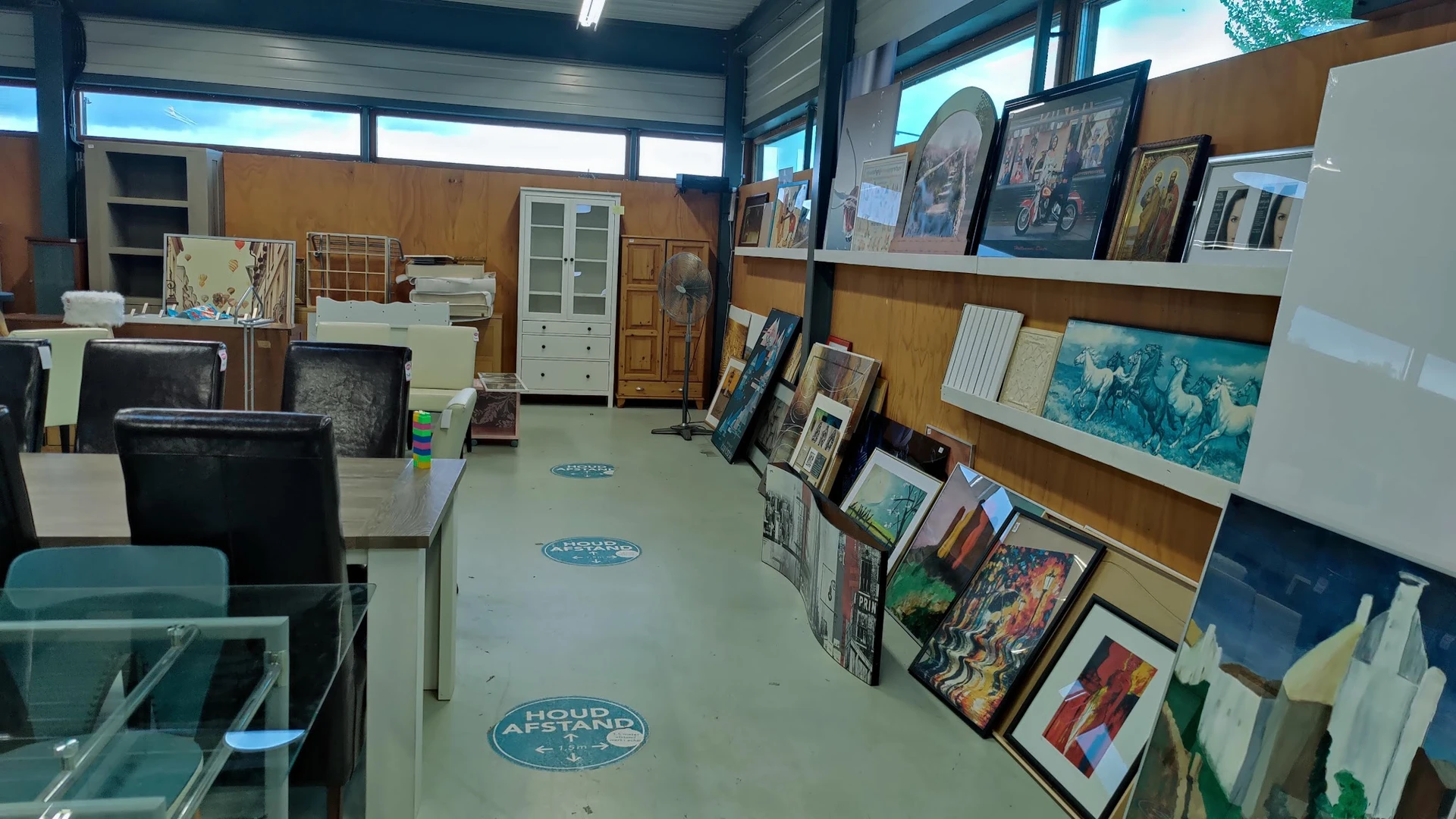 Winkelvloer met uitgestalde schilderijen, prints en kunstwerken tegen houten wanden