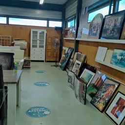 Winkelvloer met uitgestalde schilderijen, prints en kunstwerken tegen houten wanden