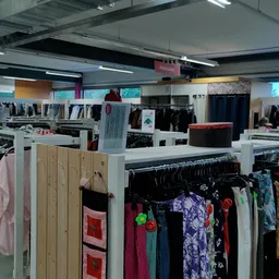 Winkelinterieur met rekken vol tweedehands kleding, witte scheidingswanden en verlichting van bovenaf