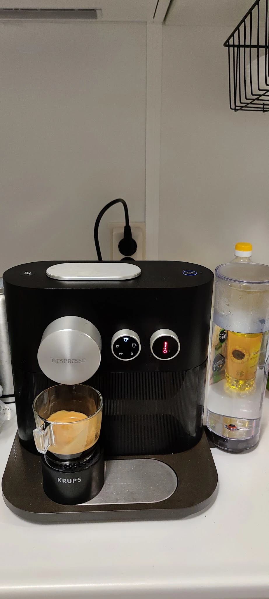 Nespresso koffiezetapparaat in zwart met zilveren accenten en waterdispenser op houten tafel