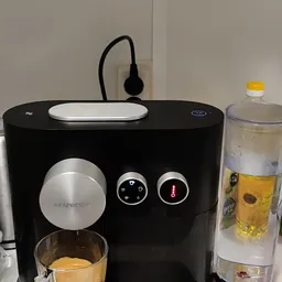 Nespresso koffiezetapparaat in zwart met zilveren accenten en waterdispenser op houten tafel
