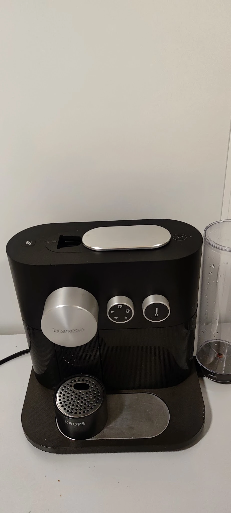 Nespresso-koffiemachine in zwart met zilveren accenten, close-up van voorkant met bedieningsknoppen