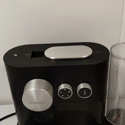 Nespresso-koffiemachine in zwart met zilveren accenten, close-up van voorkant met bedieningsknoppen