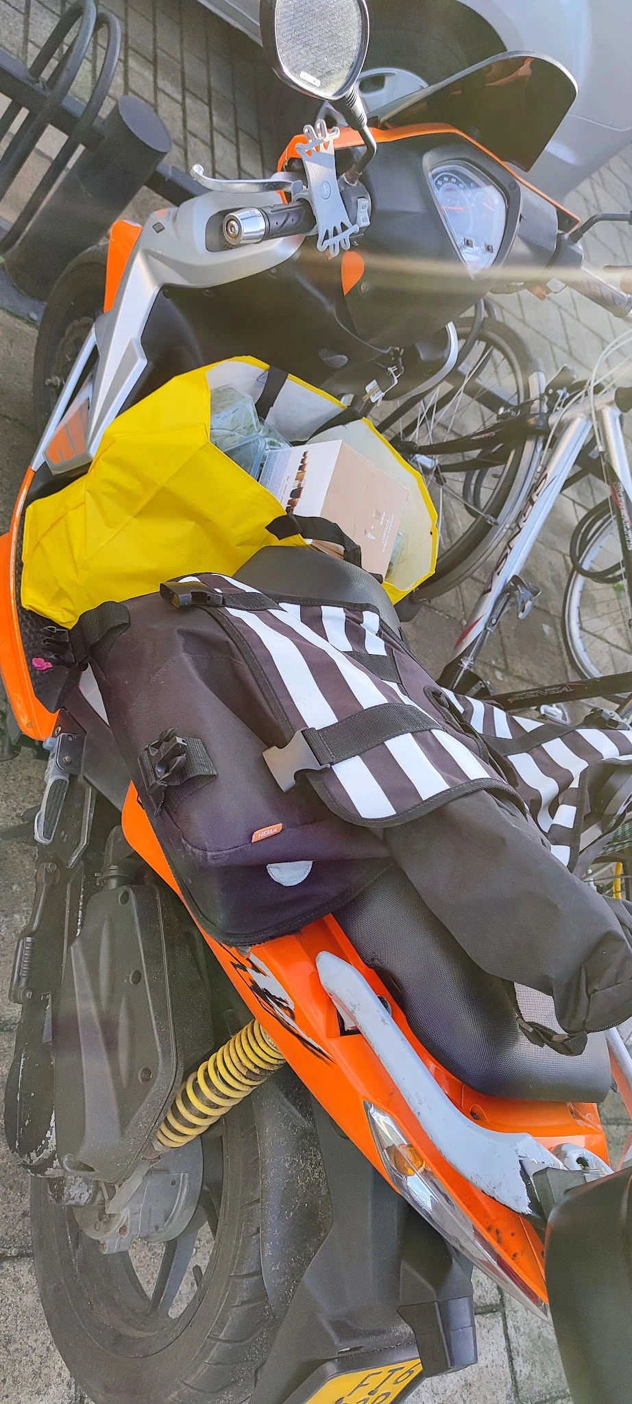 Zwart-wit gestreepte rugzak met oranje accenten en zwarte riemen, op oranje ondergrond