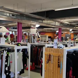 Winkelvloer met kledingrekken en paarse zuilen in een kringloopwinkel