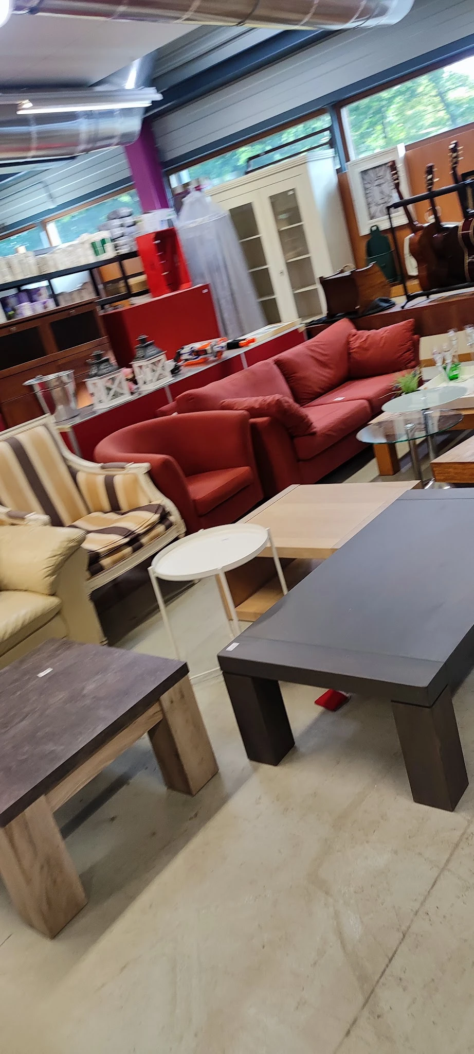 Zithoek met rode fauteuils en witte bijzettafels in kringloopwinkel
