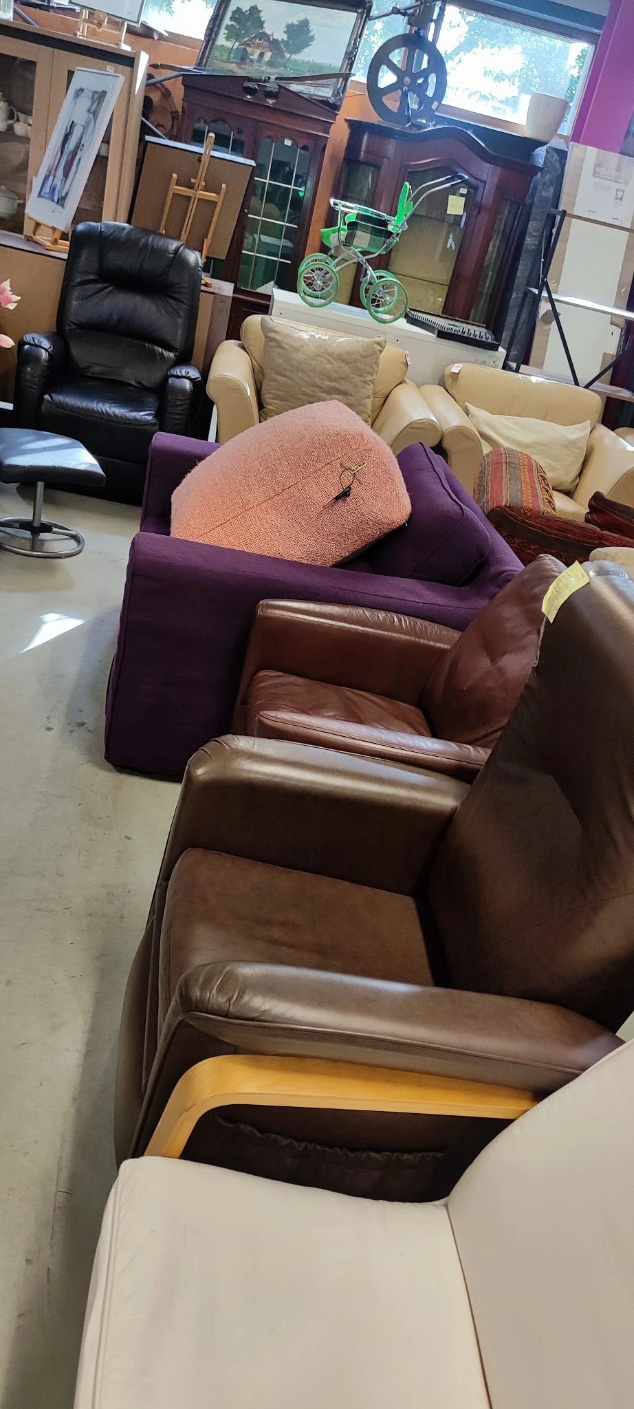 Bruin lederen fauteuil met armleuningen, gedeeltelijk zichtbaar in de winkel