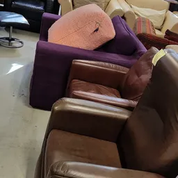 Bruin lederen fauteuil met armleuningen, gedeeltelijk zichtbaar in de winkel