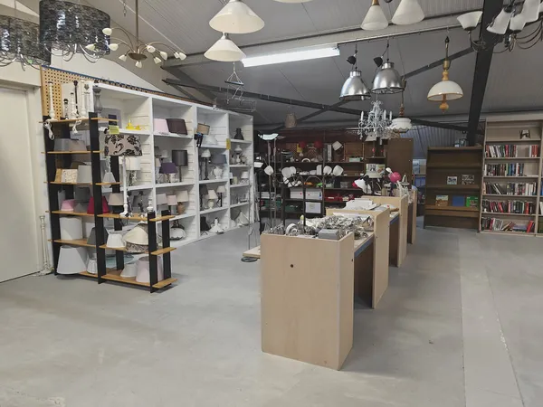 Winkelinterieur met stellingen, kastjes en toonbanken vol spullen, hanglampen aan het plafond