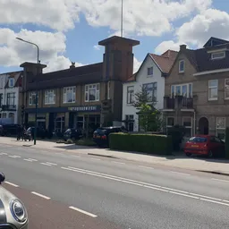 Straatgevel van kringloopwinkel met donkerblauwe pui, aangrenzen aan andere historische panden