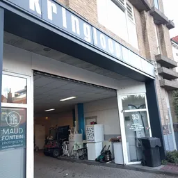 Winkelfront met grote etalageruiten, blauwe kozijnen en huisnummer 30, zicht op verlichting en deel van het interieur