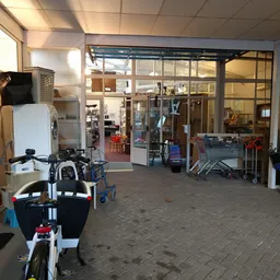 Winkelentree met glazen deuren, kinderwagens en spullen op de vloer, zicht op het interieur