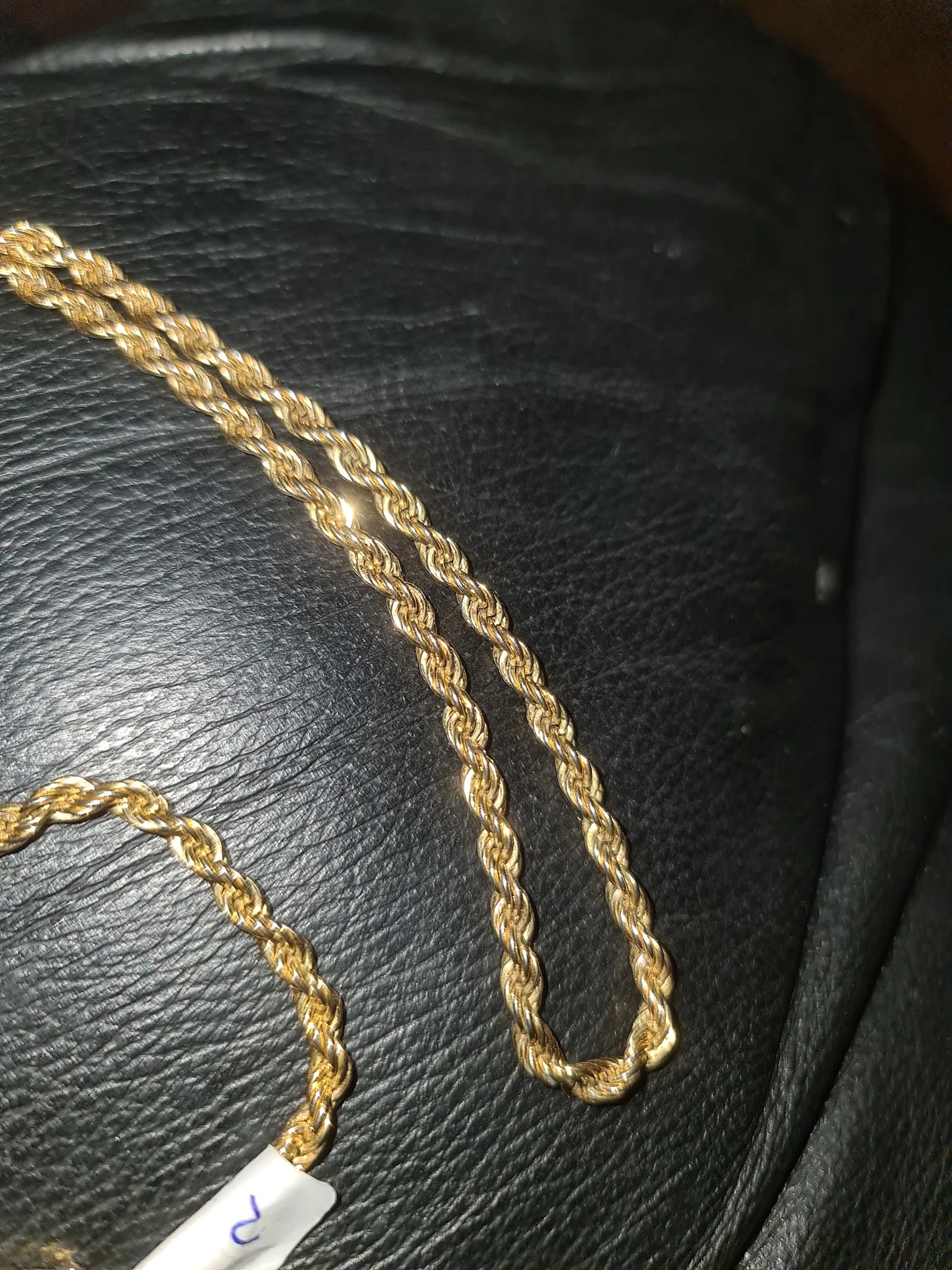 Close-up van gouden kettingen op zwart leer