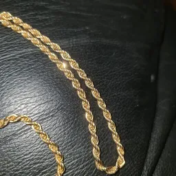 Close-up van gouden kettingen op zwart leer