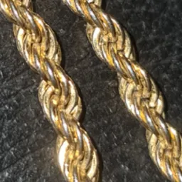 Close-up van twee gouden gedraaide kettingen op donkere achtergrond