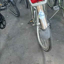 Close-up van een tweedehands fiets met Okazi-sticker op het frame, geparkeerd op asfalt