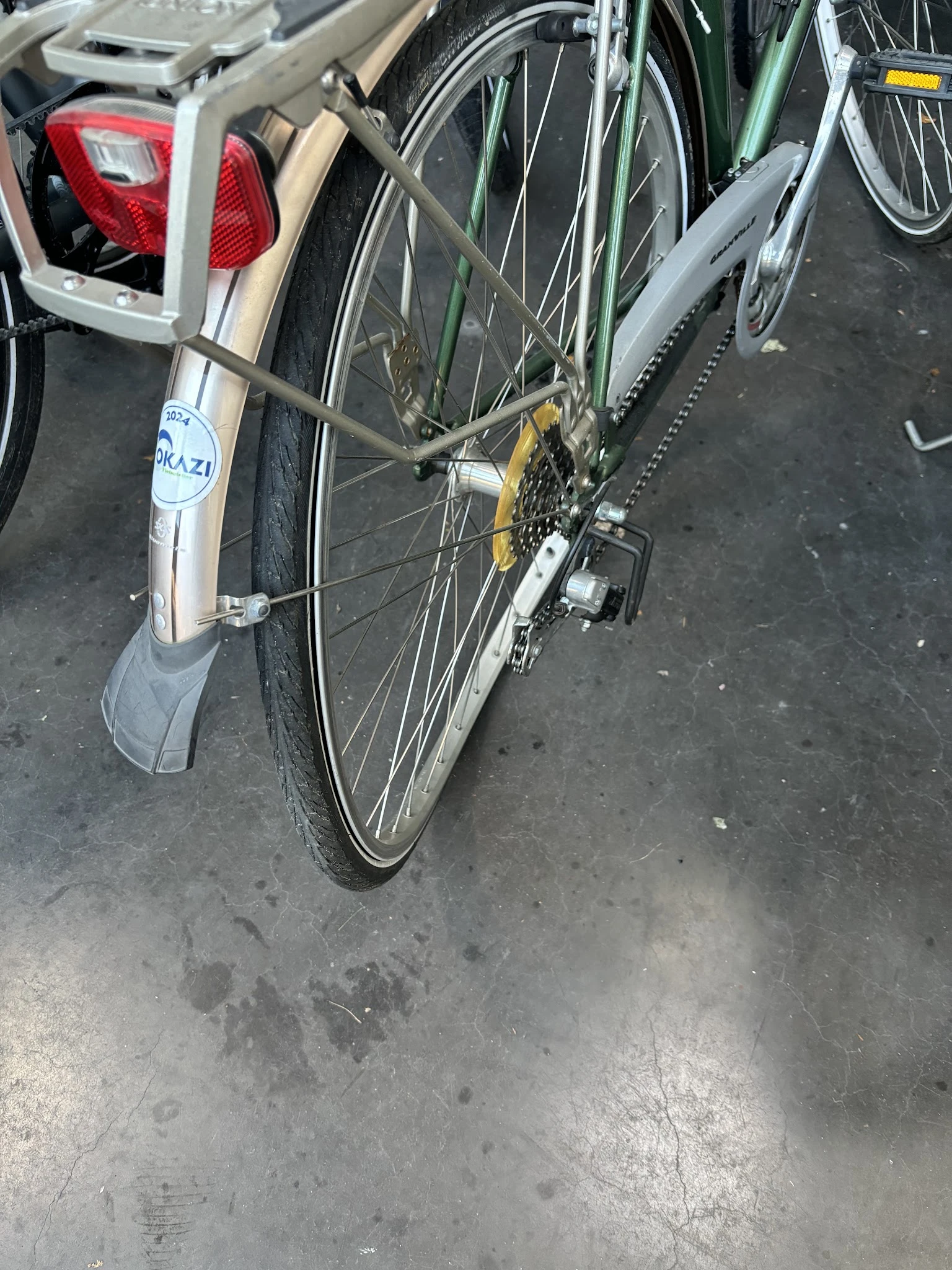 Tweedehandsfiets met grijs spatbord en geel kettingwiel op grijze ondergrond