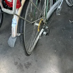Tweedehandsfiets met grijs spatbord en geel kettingwiel op grijze ondergrond