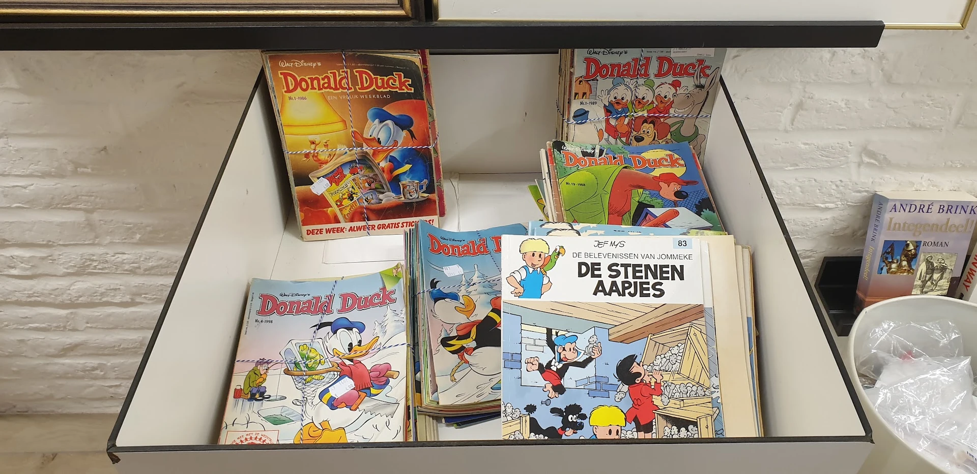 Verzameling tweedehands Donald Duck strips en boeken in een winkelkast