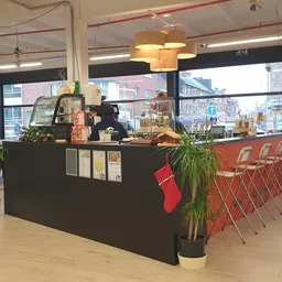 Koffiebar of lunchcounter met zwarte balie, rode stoelen en kerstdecoratie in kringloopwinkel