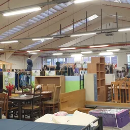 Ruim winkelinterieur met diverse meubels, kledingrekken en stellingen vol tweedehandsartikelen