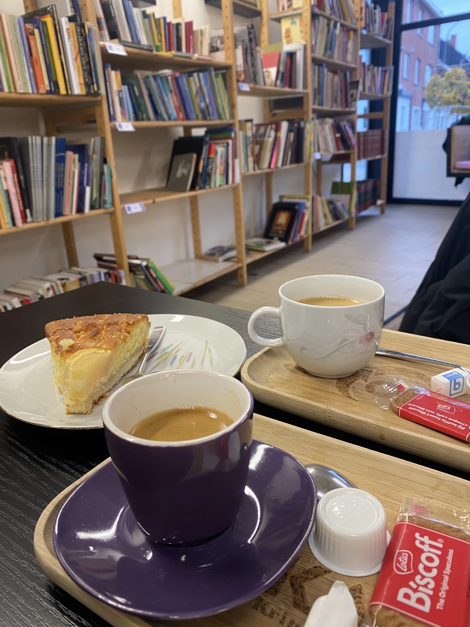 Koffiekopjes en een stuk cake op tafel in de lunchroom, met boekenkasten op de achtergrond