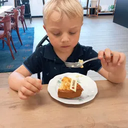 Jong kind eet uit een bord met toast en eiersalade in de lunchroom