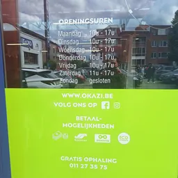 Openingsuren en contactgegevens van een winkel op een geel-groen bord