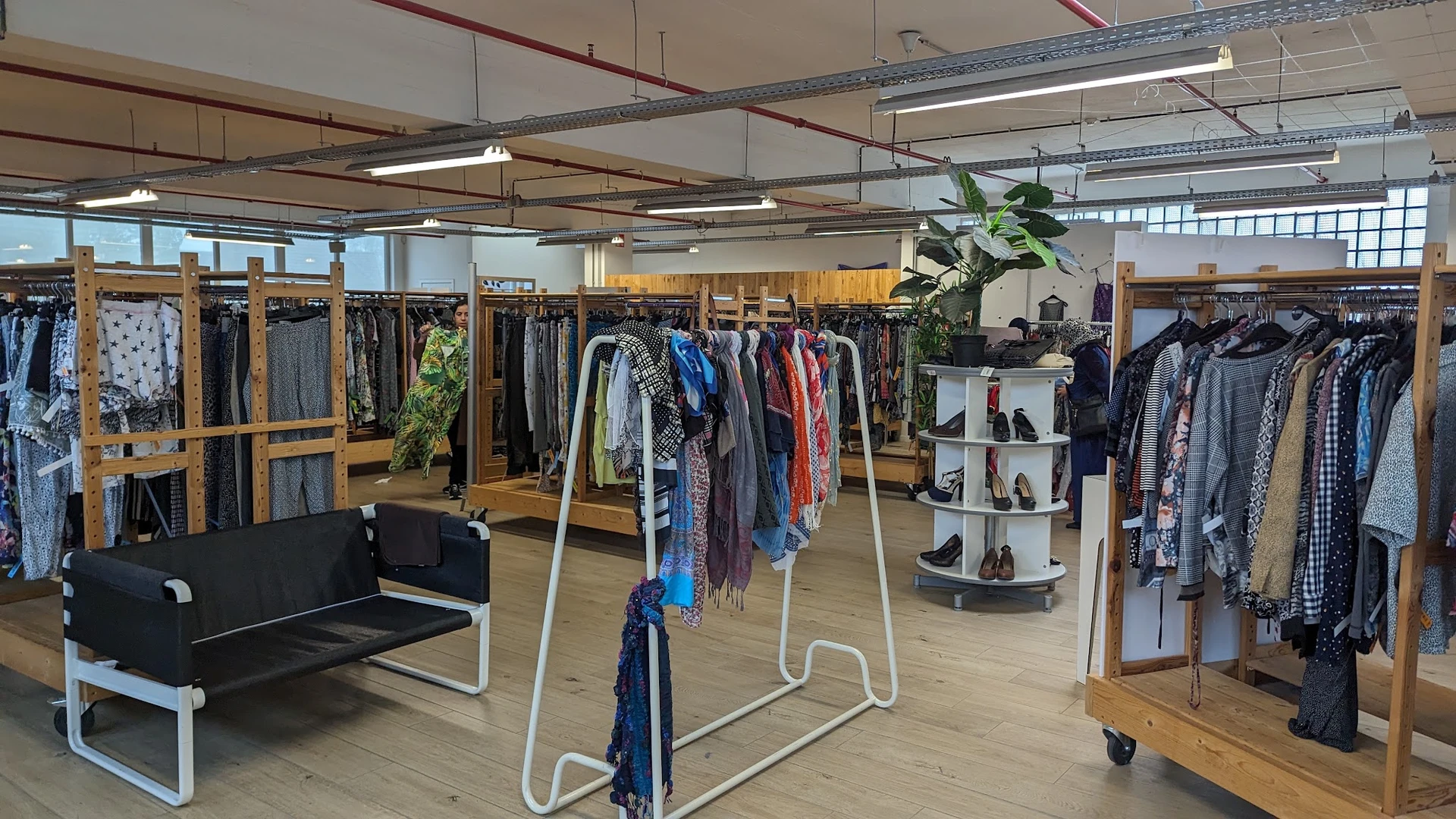 Winkelinterieur met kledingrekken, display met schoenen en zithoek in een kringloopwinkel