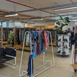 Winkelinterieur met kledingrekken, display met schoenen en zithoek in een kringloopwinkel