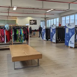 Ruime winkelruimte met kledingrekken aan beide zijden en houten bank in het midden