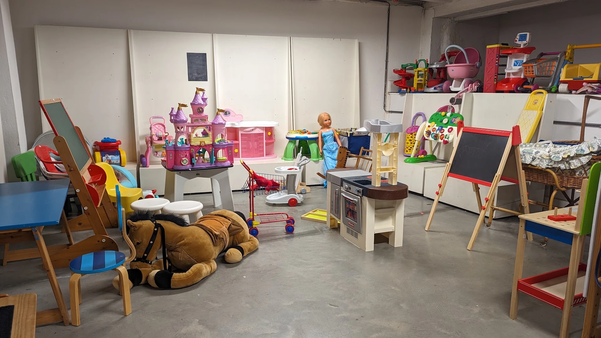 Speelgoedafdeling in kringloopwinkel met poppenhuizen, speelkeuken, tekenboard en diverse kinderspeelgoed