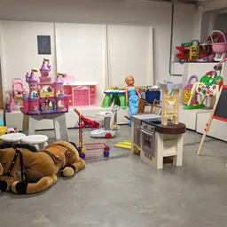 Speelgoedafdeling in kringloopwinkel met poppenhuizen, speelkeuken, tekenboard en diverse kinderspeelgoed