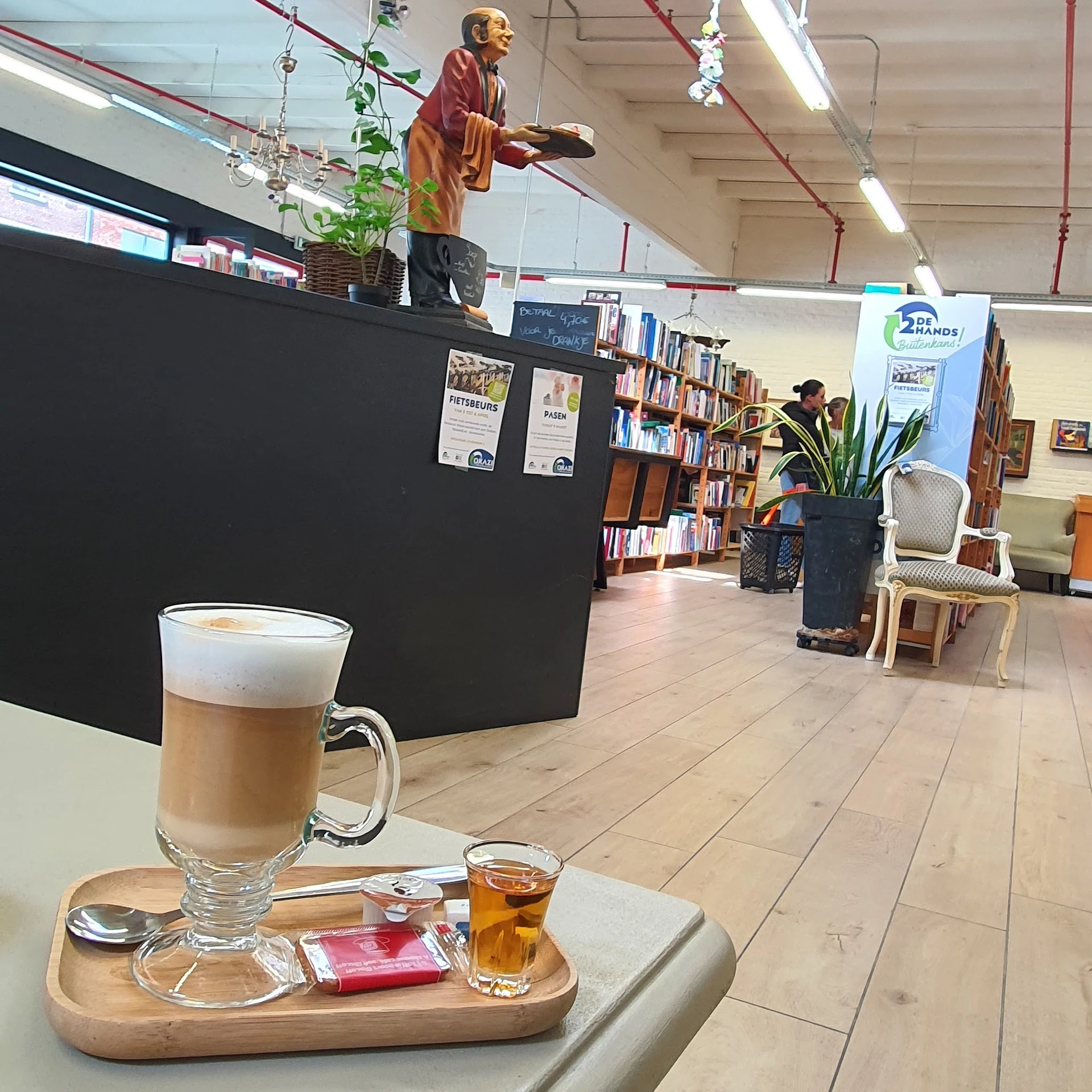 Glas cappuccino en kopje thee op tafel in de lunchroom van de winkel, boekenkasten op achtergrond