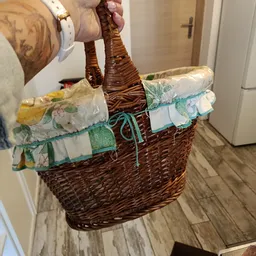 Rieten mand gevuld met opgevouwen linnengoed en textiel in verschillende kleuren