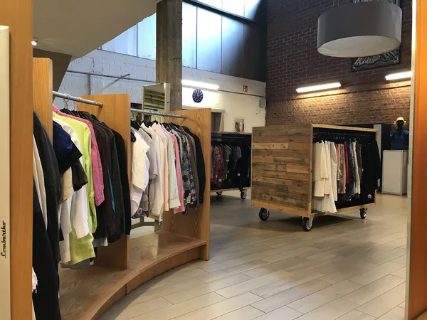 Winkelvloer met houten stellingen en rekken vol kleding in verschillende kleuren