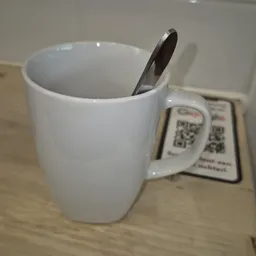Witte keramische mok met zwarte lepel en QR-codes op een houten tafel