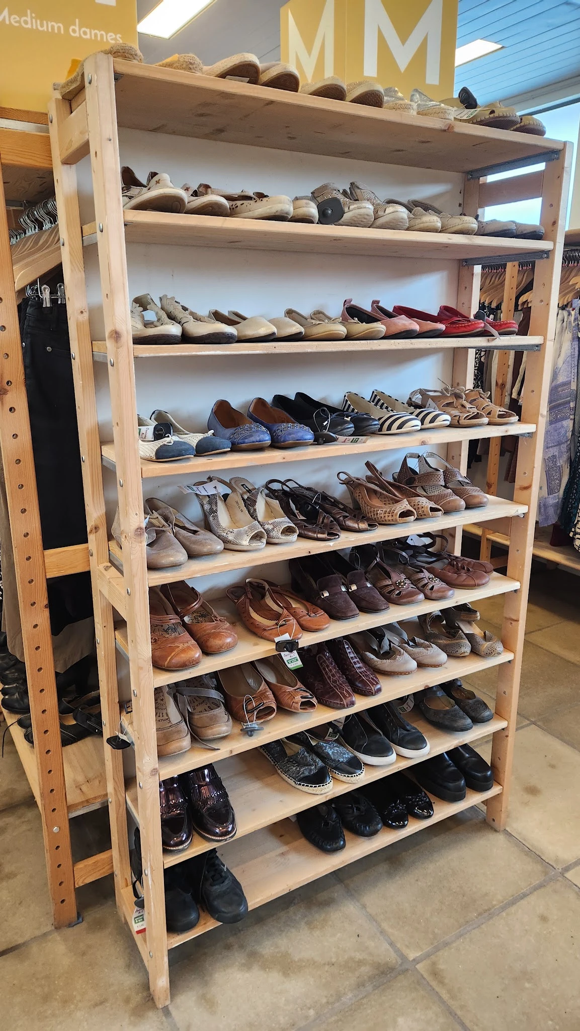 Houten schoenrekkasten met diverse tweedehands schoenen en sandalen netjes uitgestald