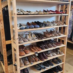 Houten schoenrekkasten met diverse tweedehands schoenen en sandalen netjes uitgestald