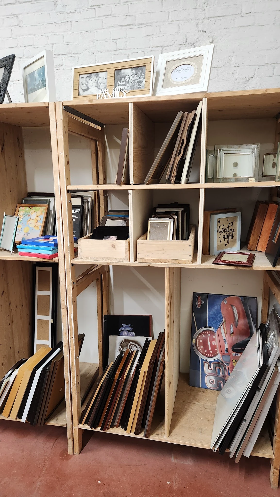 Houten stellingkast met diverse tweedehands artikelen: boeken, fotolijsten, decoratieve items en kunstwerken netjes uitgestal