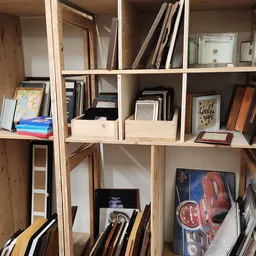 Houten stellingkast met diverse tweedehands artikelen: boeken, fotolijsten, decoratieve items en kunstwerken netjes uitgestal