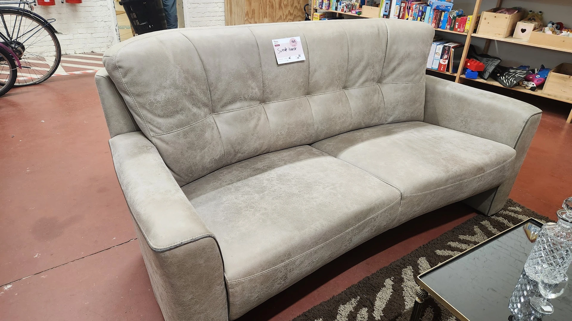 Grijze gestoffeerde tweezitsbank met quilting en arm- en rugkussens in de winkel