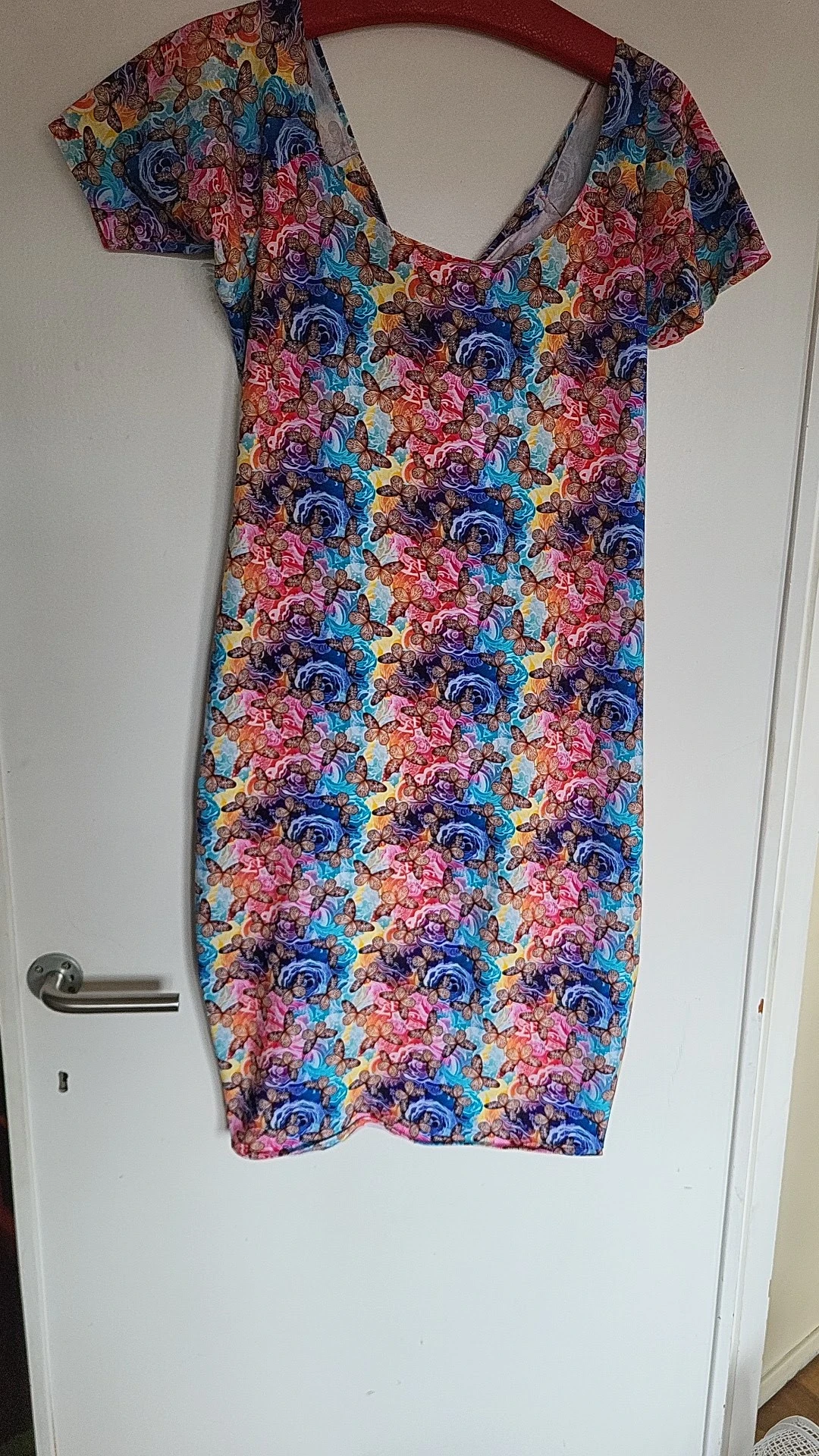 Gekleurde handdoek met bloemenpatroon in rood, blauw, paars en geel opgehangen aan een handdoekrek
