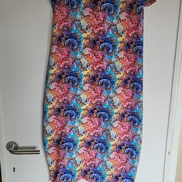 Gekleurde handdoek met bloemenpatroon in rood, blauw, paars en geel opgehangen aan een handdoekrek