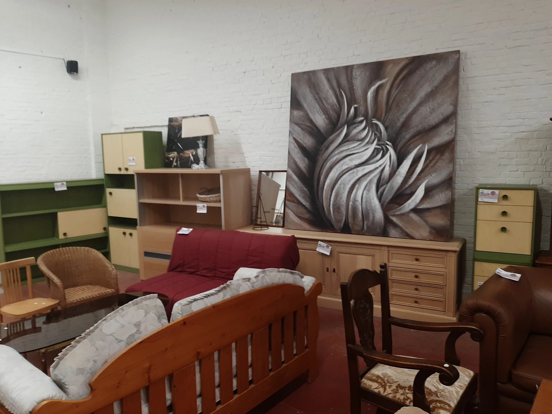 Ingerichte slaapkamer met houten bed, rode sprei, kasten en decoratie in kringloopwinkel