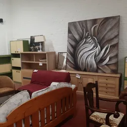 Ingerichte slaapkamer met houten bed, rode sprei, kasten en decoratie in kringloopwinkel